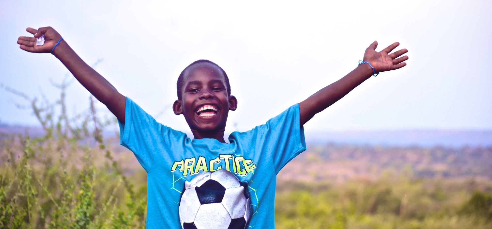Young Ugandan boy with his arm outstretched in happiness