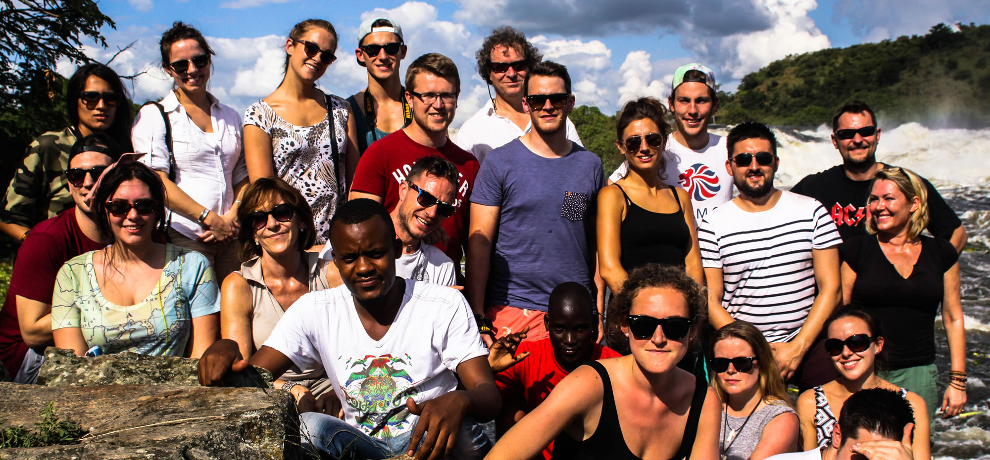 Large group of people standing in front of natural waterfall
